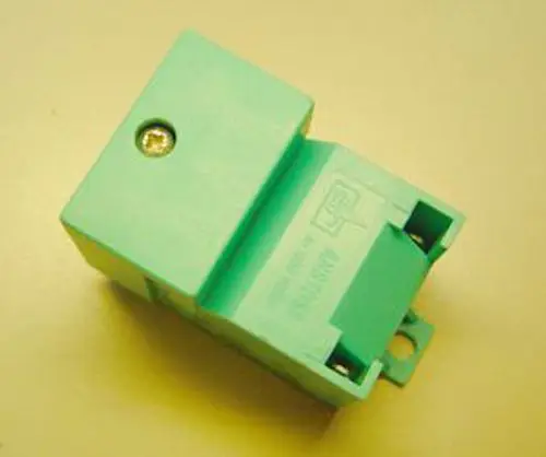 Remeha Zündtrafo in mintgrüner Farbe, mit einem sichtbaren Schraubenkontakt auf der Oberseite und einem Steckanschluss an der Unterseite.